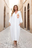 Beyaz, V yaka, göğsü nota nakışlı, cepli ve oversize uzun viskon elbise.