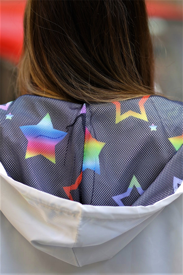 Gökkuşağı renkli yıldız desenli iç astara sahip beyaz kapüşonlu ince yağmurluk.