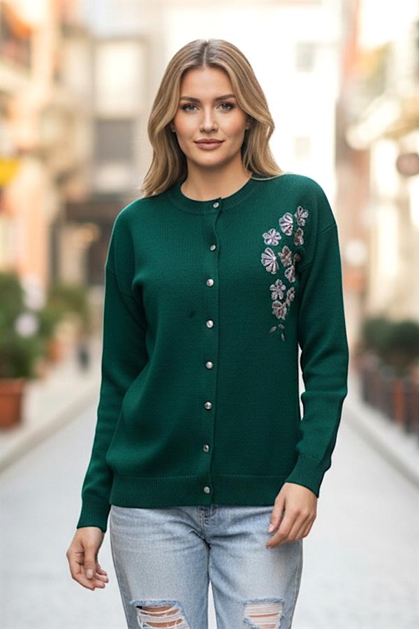 Haki renkli, çiçek nakışlı ve düğmeli triko hırka giyen bir kadın.