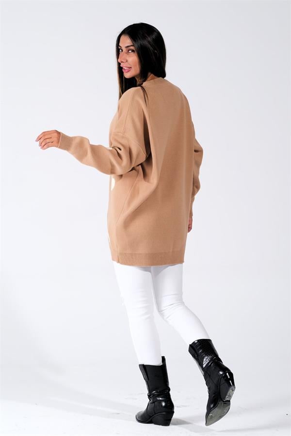 Kahverengi, uzun kollu, kabartma kalp detaylı triko kazak giyen bir kadın.