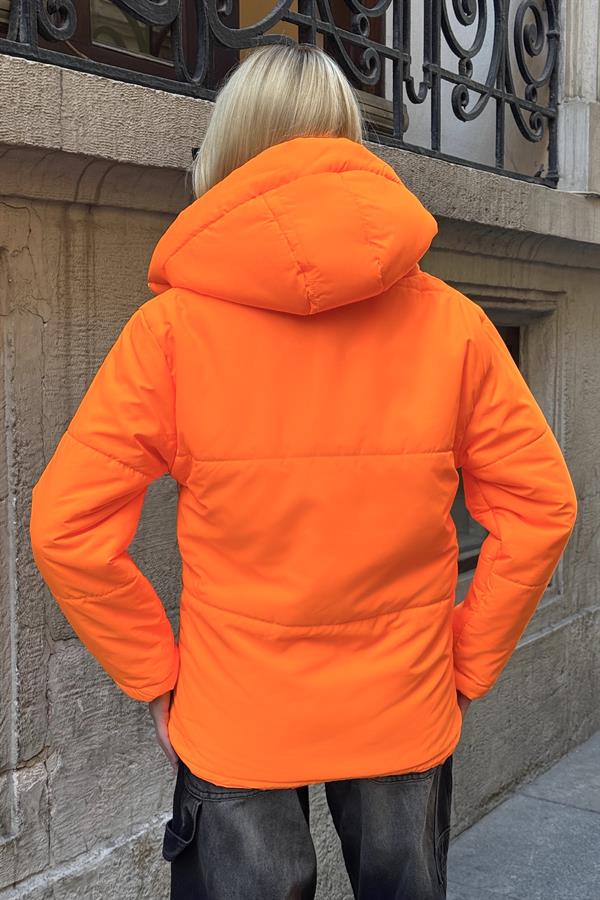Sırtı dönük, neon turuncu renkli, kapüşonlu ve şişme bir mont giyen kişi.