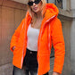 Neon turuncu renkli, kapüşonlu ve fermuarlı şişme mont.