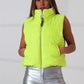 Neon yeşil renkli, dik yakalı, fermuarlı ve cepli kısa şişme yelek.