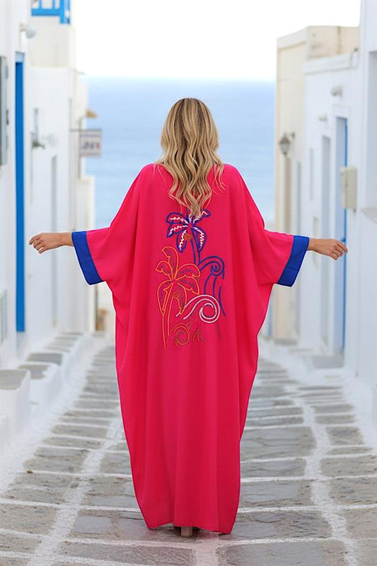 Sırtında palmiye nakışı bulunan, mavi detaylı, pembe renkli, yarasa kollu uzun elbise.