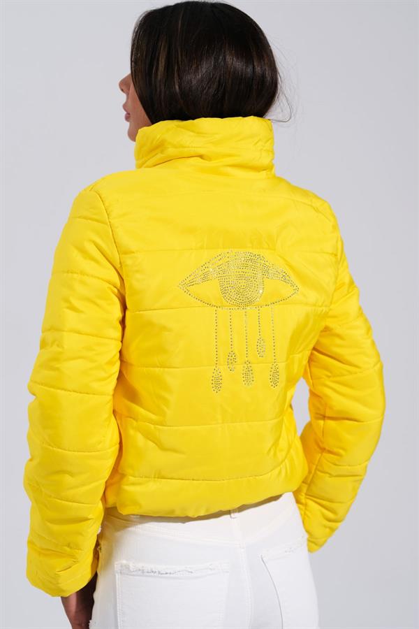 Sırtında taş işlemeli göz detayı bulunan, dik yakalı, kısa sarı şişme mont.