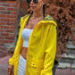 Sarı renkli, fermuarlı, cepli ve yıldız desenli kapüşona sahip ince kadın yağmurluğu.