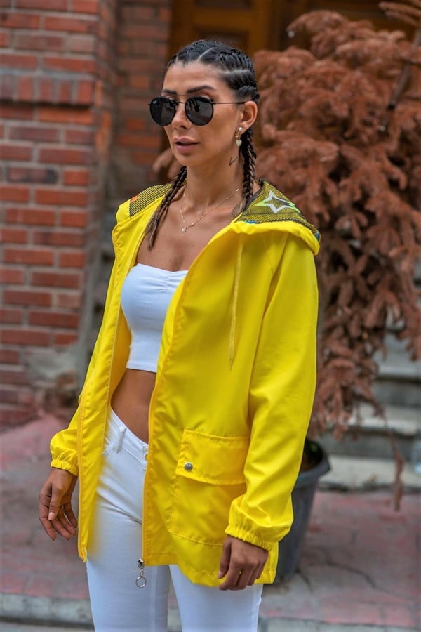 Sarı renkli, fermuarlı, cepli ve yıldız desenli kapüşona sahip ince kadın yağmurluğu.