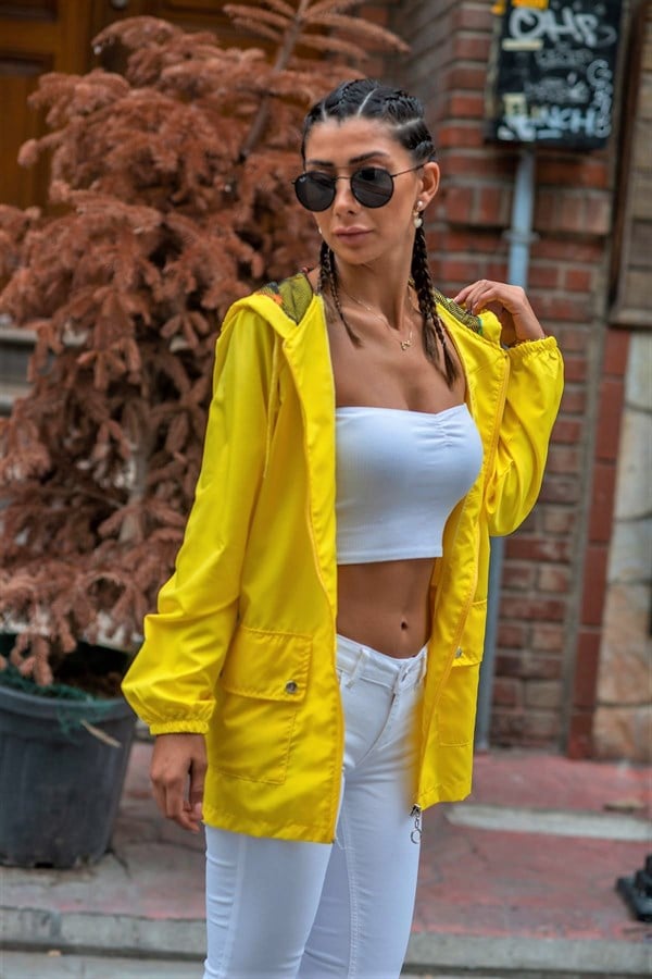 Kapüşonlu, fermuarlı ve cepli sarı renkli ince kadın yağmurluk.