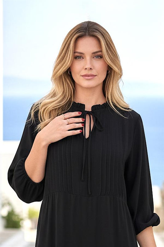 Siyah renkli, yakası bağlamalı ve pile detaylı diz boyu viskon elbise.