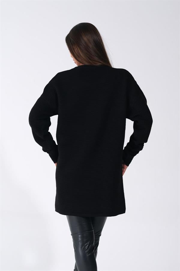 Siyah bisiklet yaka, fitilli dokuya sahip uzun triko kazak giyen bir kadın.