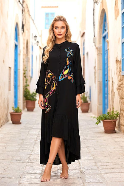 Siyah, dik yakalı, volanlı kollu ve önü nakışlı, asimetrik kesim uzun viskon elbise.