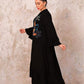 Siyah renkli, dik yakalı, kolları ve etek ucu fırfırlı, önü nakışlı, uzun oversize elbise.