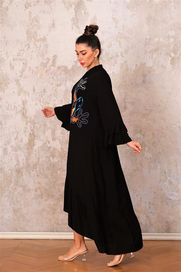 Siyah renkli, dik yakalı, kolları ve etek ucu fırfırlı, önü nakışlı, uzun oversize elbise.