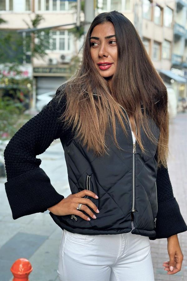 Siyah dik yakalı, fermuarlı, kolları triko detaylı şişme mont.
