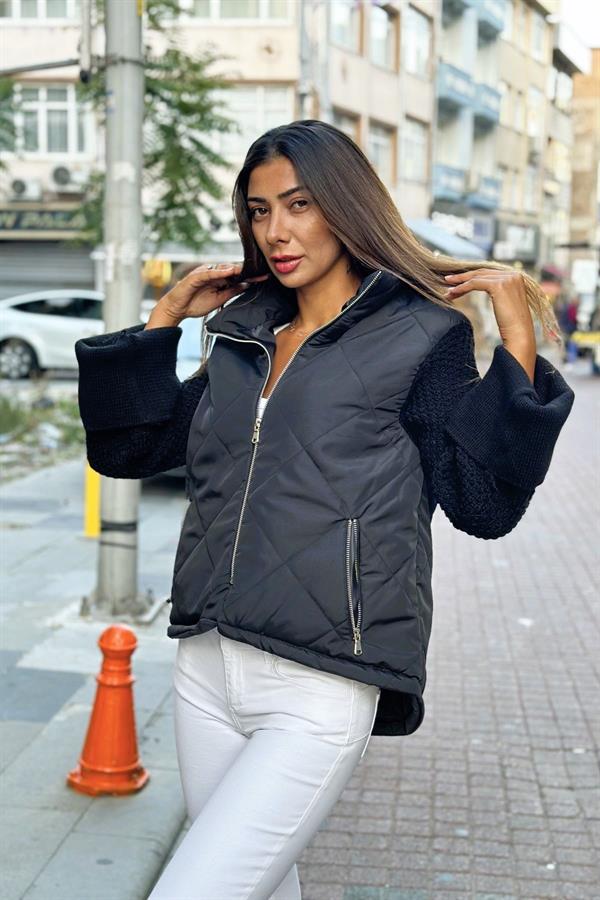 Siyah dik yakalı, fermuarlı, şişme gövdeli ve triko kollu mont.