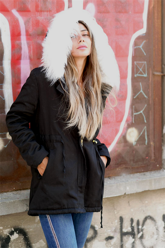 İçi kürklü, beyaz kürk detaylı kapüşona sahip siyah gabardin mont.