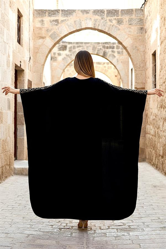 Siyah renkli, kolları desenli, uzun ve oversize kesim kadın elbisesi.