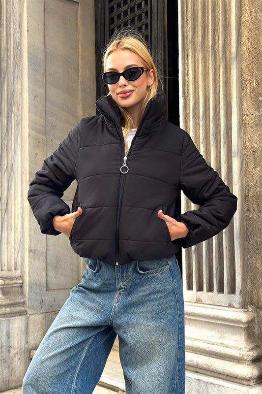 Siyah renkli, dik yakalı, fermuarlı ve kısa kesim şişme mont.