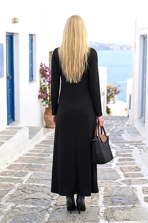 Siyah uzun kollu modal elbise giyen sarışın bir kadın arkadan görünmektedir.