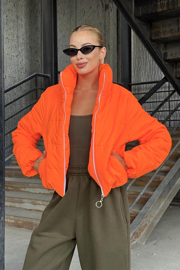 Dik yakalı, fermuarlı ve canlı turuncu renkte kısa şişme mont.