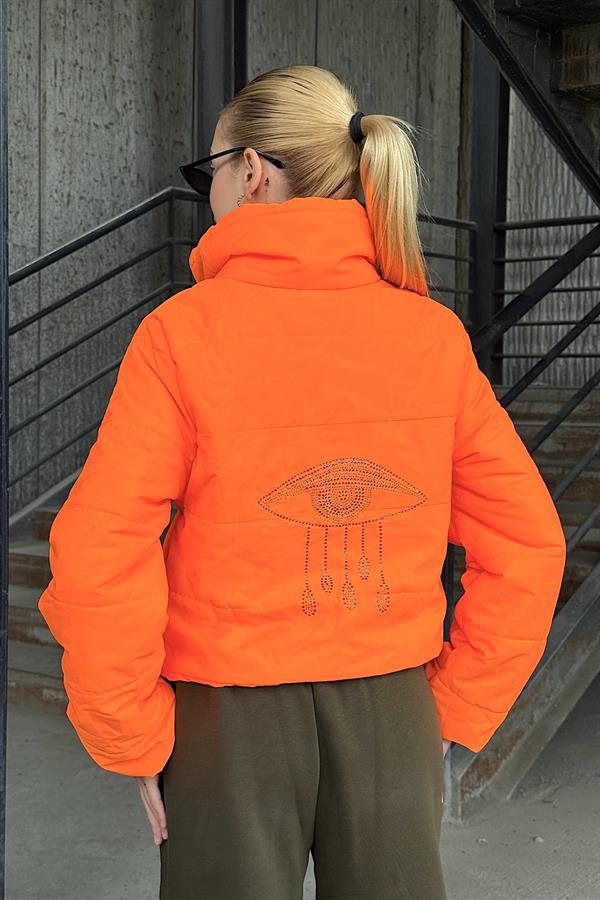 Sırtında taş işlemeli göz detayı bulunan, dik yakalı, kısa turuncu şişme mont.