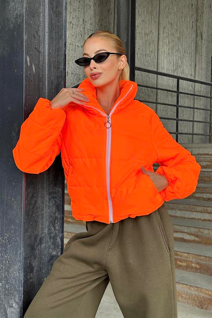 Dik yakalı, fermuarlı ve parlak turuncu renkte kısa şişme mont.